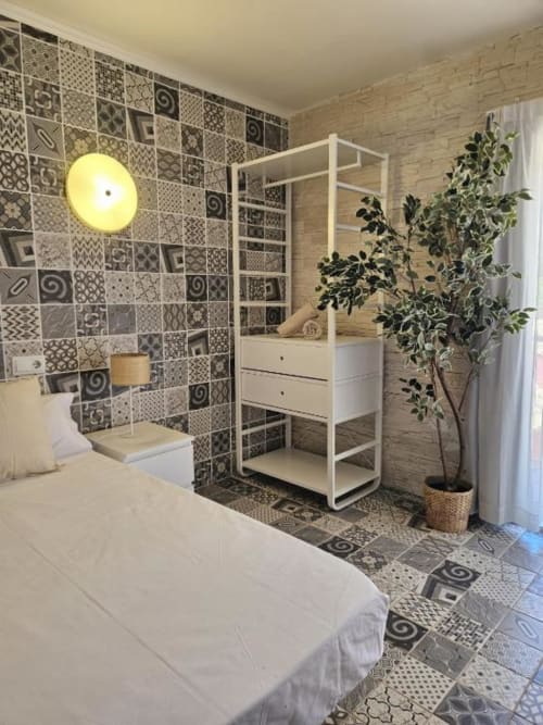 Habitación moderna en el hostel Villa Palmer de Paguera con cama blanca, pared de azulejos decorativos y baño abierto blanco