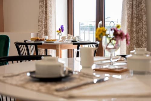 Elegante sala colazione di AgriBio Villa Ribes ad Altamura con tavoli rotondi, fiori freschi e vista dal balcone