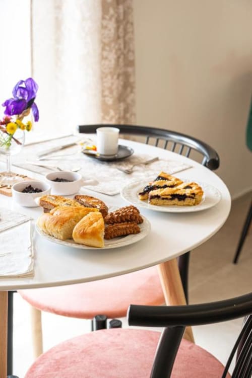 Elegante colazione ad AgriBio Villa Ribes con pasticcini, caffè e fiori di iris freschi su tavolo in marmo bianco