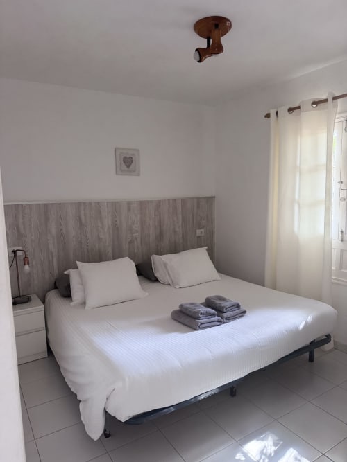 Dormitorio limpio con ropa de cama blanca y toallas dobladas en el apartamento Kamalahouse SL, Corralejo