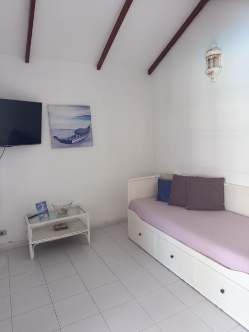 Dormitorio moderno de Kamalahouse en Corralejo con cama blanca, TV, arte náutico y decoración con vistas al océano