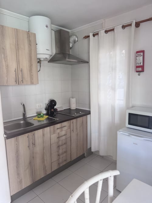 Cocina moderna en el apartamento La Concha del Mar de Kamalahouse, Corralejo con muebles de madera, encimera negra, campana extractora y
