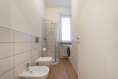 Bagno moderno nell'appartamento La Magnolia a Firenze con doccia, doppio lavabo, toilette e pavimentazione in legno