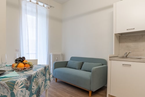Moderno soggiorno in appartamento a Firenze con divano blu, tavolo da pranzo con frutta, e cucina su Holiday-rent.it La