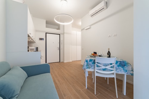 Appartamento La Magnolia a Firenze con zona giorno moderna, divano blu, tavolo da pranzo, angolo cottura e dettagli circolari