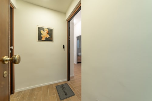 Ingresso luminoso dell'appartamento La Magnolia a Firenze con porte in legno, zerbino accogliente e quadri incorniciati