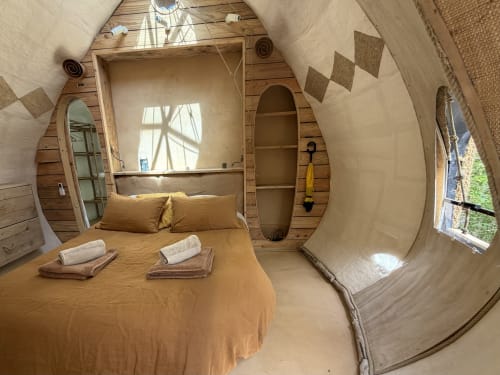 Cozy wooden barrel bedroom at Le Patio aux Oiseaux BnB in La Ciotat with bed, shelving and natural light