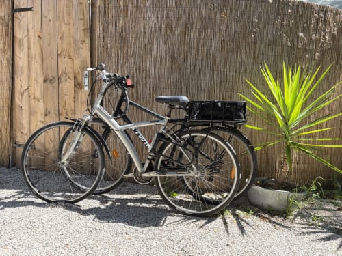Vélo avec panier à bagages garé contre une clôture en bois au Patio aux Oiseaux, La Ciotat