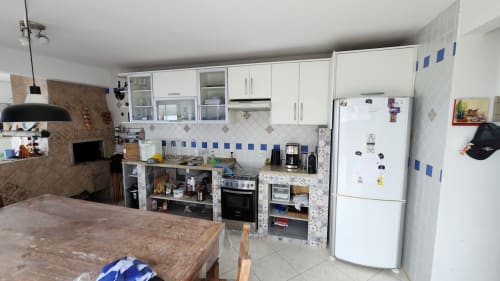 Cozinha moderna na villa Philia, Florianópolis com armários brancos, geladeira branca e backsplash em azulejo