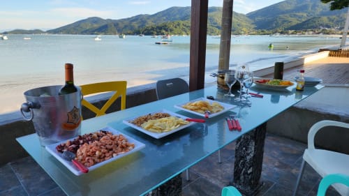 Jantar à beira-mar no hotel Philia em Florianópolis com tábuas de frutos do mar, vinho e vista para a baía