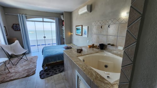 Quarto do hotel Philia em Florianópolis com vista para o mar, banheira de hidromassagem, cama e acesso à varanda oceânica