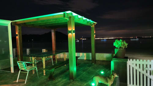 Terraço de villa frente ao mar à noite com pérgola iluminada, mesa de jantar e vista para o mar no hotel Philia, Florianópolis