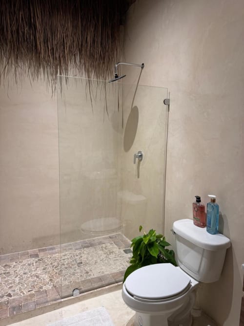 Baño moderno en Ala Residencias Villa La Guardia con ducha de cristal, inodoro blanco y plantas decorativas