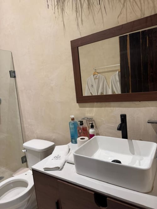 Baño moderno en Ala Residencias de Chetumal con lavamanos blanco, mueble de madera oscura y paredes con azulejos beige