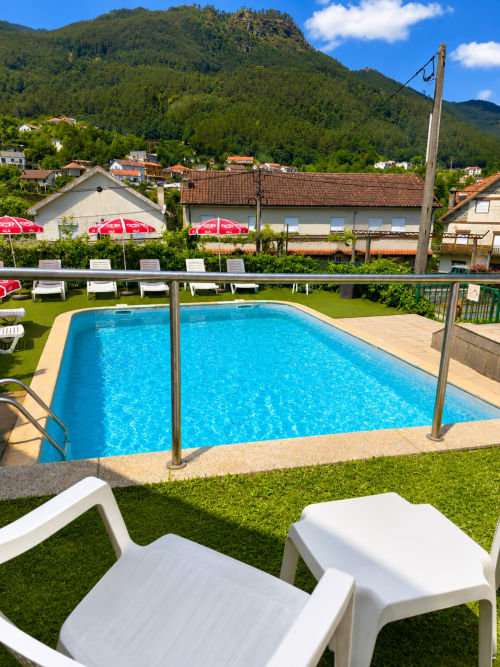 Piscina da Pousada Serrana Gerês em Gerês com espreguiçadeiras, vista para as montanhas e áreas do resort