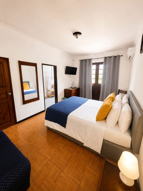 Quarto moderno da Pousada Serrana Gerês com cama queen, vista para a montanha, TV de tela plana e pisos em azulejo