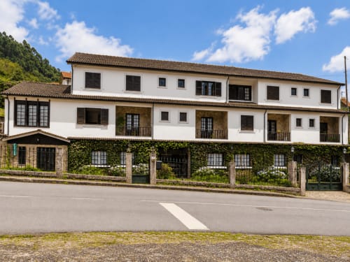 Exterior do hotel Serrana Gerês, edifício colonial branco com fachada de pedra coberta de hera na serra de Gerês, Portugal