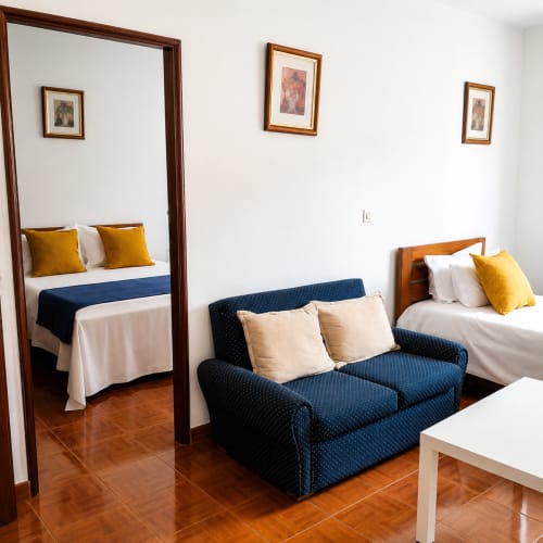 Quarto familiar da Serrana Gerês Inn com camas, sofá, estruturas de madeira e detalhes em amarelo