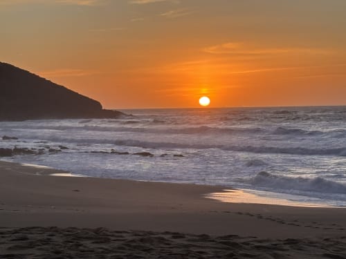 Golden sunset over Nazaré beach with waves and cliffs at Casa na Onda hotel