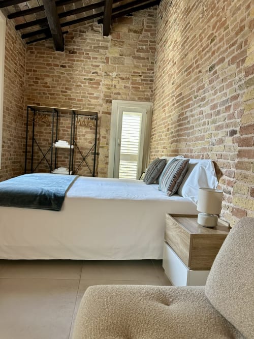 Modern bedroom suite at NOUA LIVING Ravenna B&B with exposed brick walls, white bedding, and contemporary furnishings