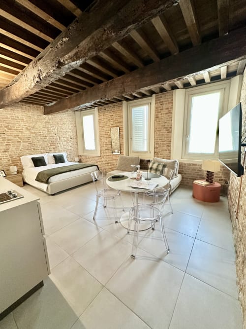 Moderno loft a NOUA LIVING a Ravenna con mattoni a vista, travi in legno, letto, tavolo da pranzo e TV