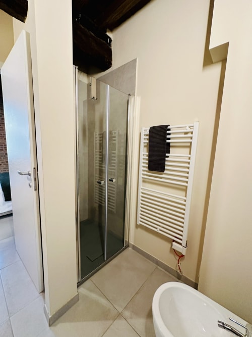 Bagno moderno nella Suite 4 di NOUA LIVING, Ravenna. Cabina doccia in vetro, scaldasalviette bianco e wc.