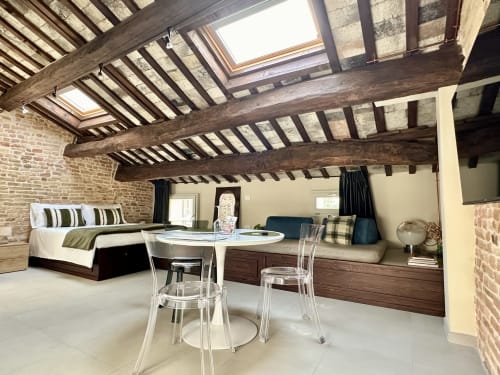 Suite 5 a NOUA LIVING a Ravenna: ampio loft con travi in legno a vista, letto, zona pranzo, muri in mattoni