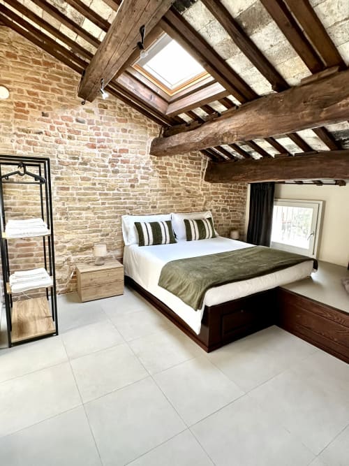 Camera da letto rustica con mattoni a vista, travi in legno, lucernari e letto matrimoniale presso NOUA LIVING a Ravenna