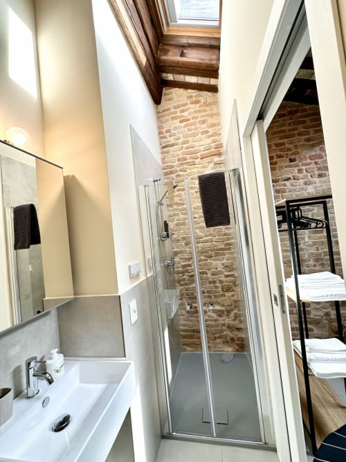 Moderno bagno con doccia nell'appartamento NOUA LIVING a Ravenna, muri in mattoni a vista e lucernario