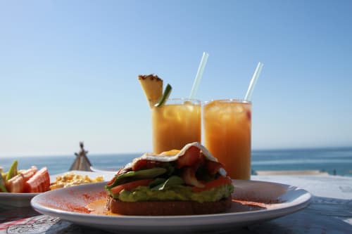 Tostadas de aguacate con tocino y bebidas tropicales con vistas al océano en Vidasoul, restaurante frente al mar, La Vinorama México
