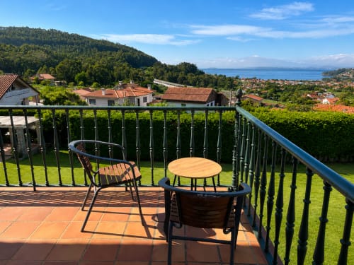 Terraza con vistas al mar de la casa Holibai en Baiona, España. Mesa y sillas de madera con vistas a la bahía.