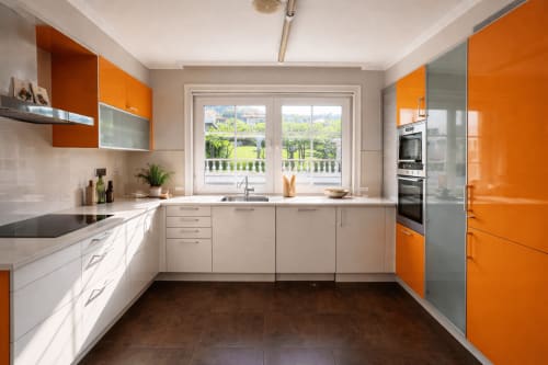 Cocina moderna con muebles naranjas y blancos, vistas al mar y jardín en la casa Mar y Sol de Baiona