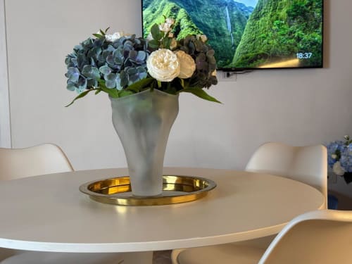 Tavolo da pranzo rotondo elegante con composizione floreale di ortensie blu e rose crema in vaso bianco, Casa Lounge Istria Cagliari