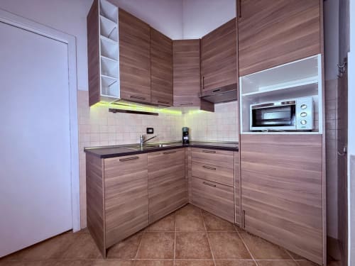 Cucina moderna in legno nell'appartamento Casa Cavour presso Casa Lounge Istria, Cagliari, con illuminazione gialla e acciaio inox