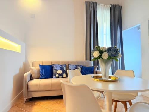 Moderno appartamento Casa Cavour a Cagliari con divano beige, cuscini blu, tavolo rotondo e vista città
