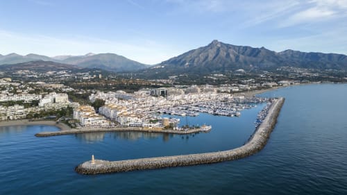 Aerial view of HomyMarbella in Elviria with marina, mountain backdrop, and Mediterranean coastline