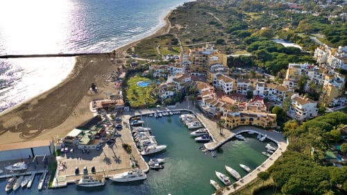 Aerial view of HomyMarbella beachfront resort in Elviria with marina, pools, and Mediterranean coastline