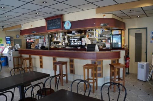 Intérieur du Bar La Pinède à Saint-Jean-de-Monts avec comptoir en bois et sièges de bar