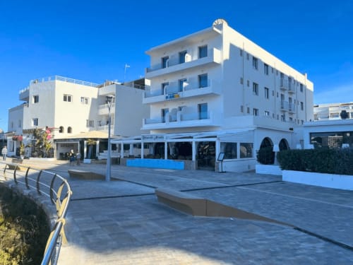 Hotel de playa Apartamentos Playa Sol en Es Canar con arquitectura mediterránea blanca y detalles azules