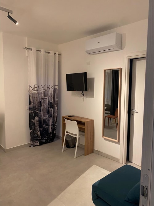 Modern hotel room in Civitanova del Sannio with desk, TV, air conditioning, and New York curtain decor