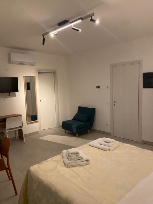 Modern hotel room at RL GROUP in Civitanova del Sannio with bed, dark armchair, TV, air conditioning, and contemporary