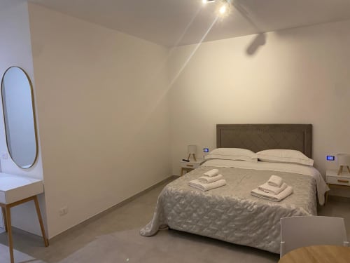 Modern bedroom at RL GROUP in Civitanova del Sannio with queen bed, oval mirror, and ambient lighting