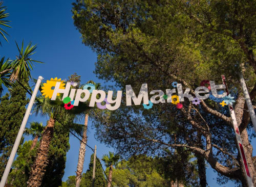 Cartel Happy Market con flores coloridas y palmeras en Apartamentos Playa Sol en Es Canar