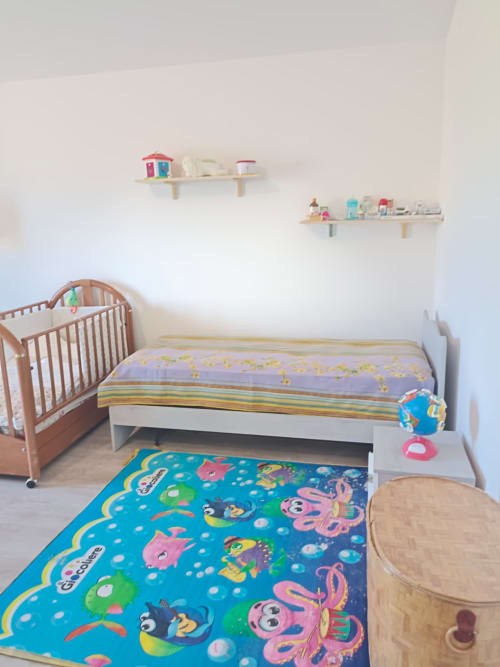Bright child's bedroom at Tales of Abruzzo with crib, bed, colorful sea-themed rug, wall shelves, and wooden furniture in