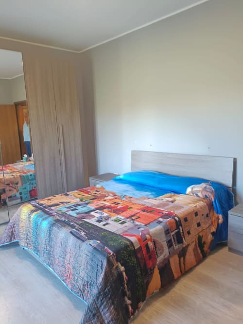 Bright bedroom at Tales of Abruzzo Atessa with colorful patterned bedding, blue pillows, wooden bed frame, mirror, and