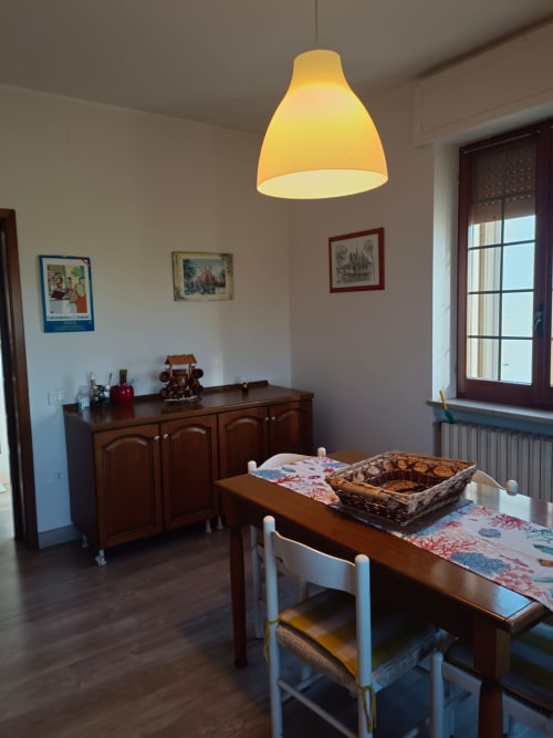 Dining area in Residenza Montemarcone apartment, Atessa, with wooden table, yellow pendant lamp, and dark wood cabinet