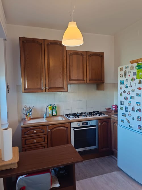 Modern kitchen in Atessa apartment with wooden cabinets, gas stove, light blue refrigerator, and pendant lamp