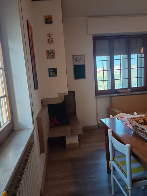 Bright apartment living area with dining table, fireplace, large windows overlooking city, and decorative wall art at Tales