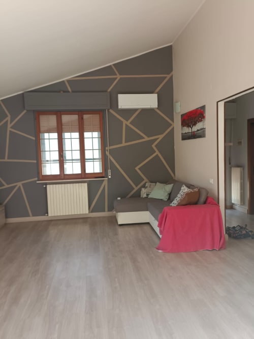 Modern apartment living room at Tales of Abruzzo, Atessa, with geometric accent wall, sofa, and city views