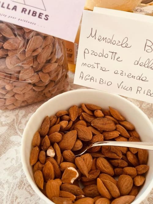 Mandorle in ciotola bianca con note scritte a mano del menu italiano presso AgriBio Villa Ribes, Altamura